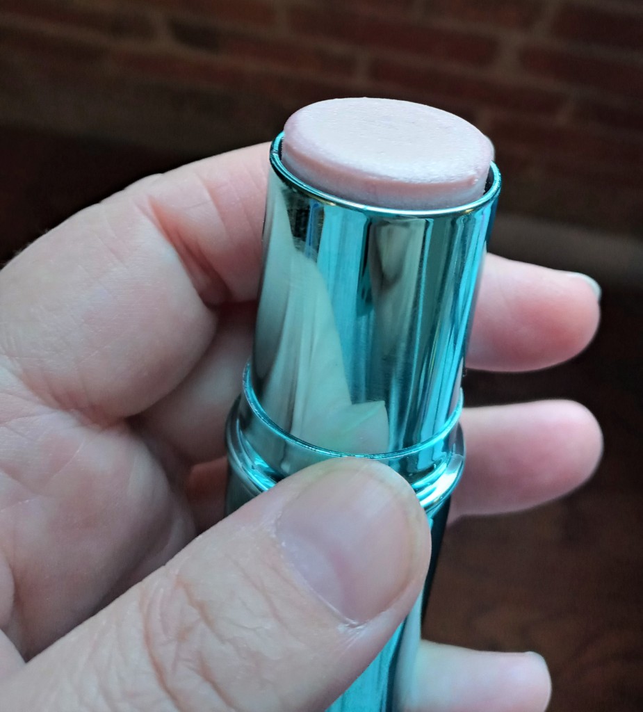 the Curious solid perfume stick, open and showing the light, shimmery surface of the fragrance