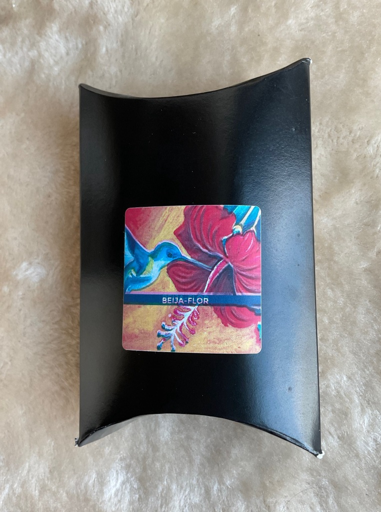 The Beija-Flor pillow box bearing a colorful image of a blue humming bird sipping nectar from a pink flower