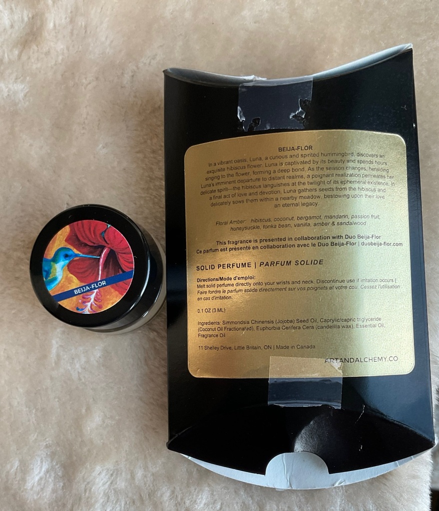 The Beij-aFlor solid perfume and back of the pillow box, which tells the story of Luna the hummingbird who is captivated by a beautiful hibiscus flower and sows its seeds as a legacy