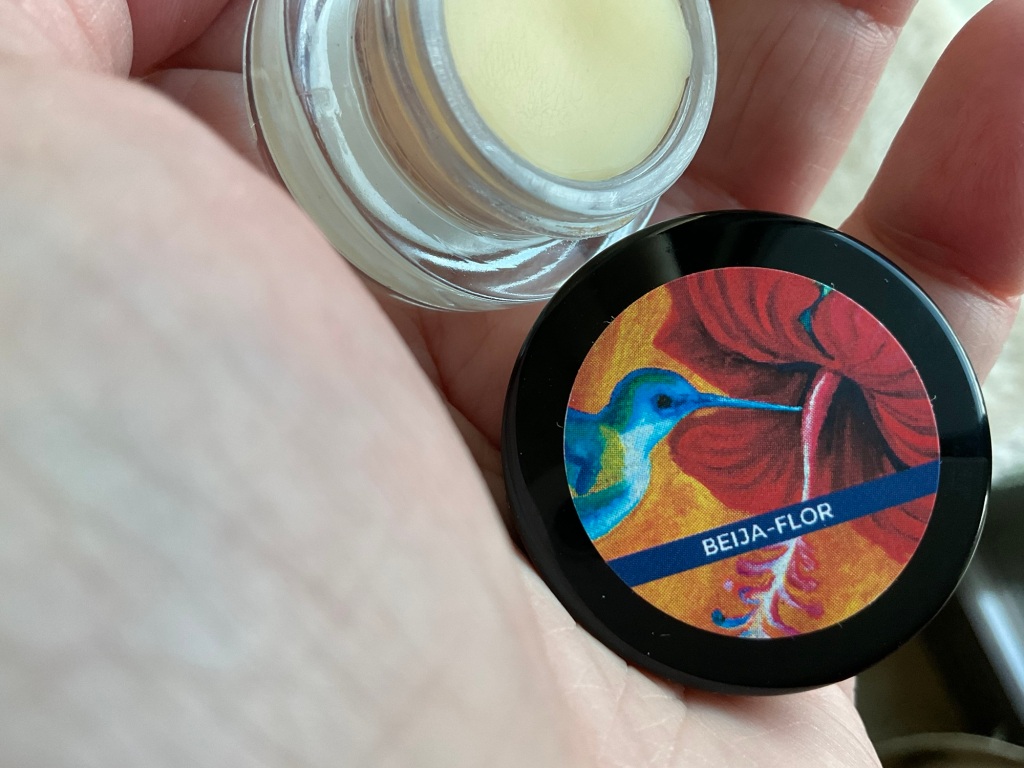 The Beija-Flor solid perfume opened and held in a woman's hand