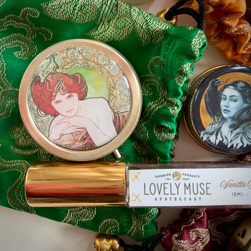 A close-up image of lockets, tins and the EDP spray bottle from The Lovely Muse Apothecary, showing the detail and design on the labels